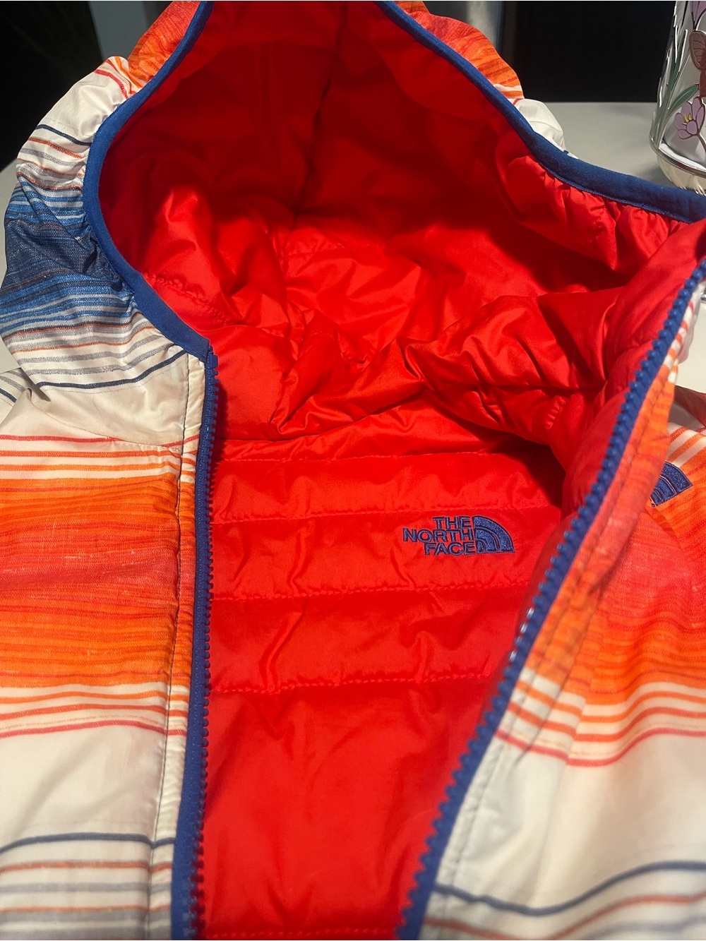 The North Face reversible Solid Red or Vibrant Striped side Puffer Jacket.